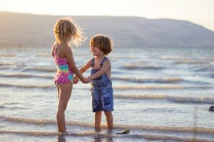 Two children holding hands on the beach